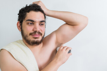 Caucasian young man with brown eyes and beard, Using antiperspirant, naked torso and towel on neck.