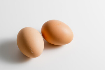 Two brown organic fresh raw eggs. Cut out and isolated on white background with soft shadows for added dimension.