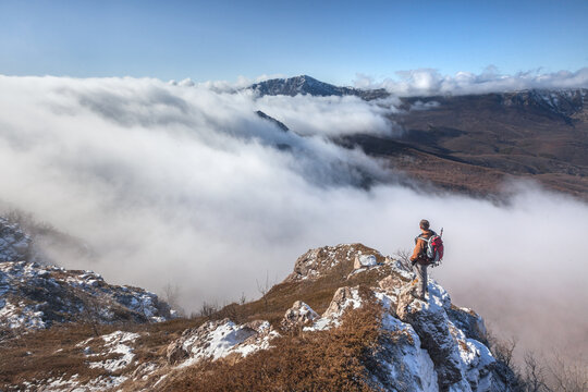 Man on a hike against the background of mountains and white clouds