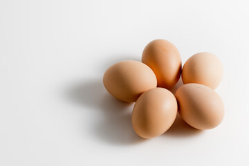 Five brown organic fresh raw eggs. Cut out and isolated on white background with soft shadows for added dimension.