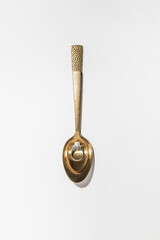pearl ring in a golden spoon on a white background
