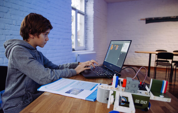 The boy is programming on a laptop. Scratch robot programming. Gigo robot programming