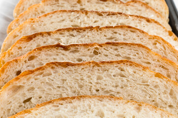 Freshly homemade bread sliced on a baking paper in a baking tray, light and airy inside with a crunchy rustic crust.