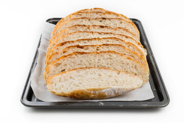 Freshly homemade bread sliced on a baking paper in a baking tray, light and airy inside with a crunchy rustic crust.