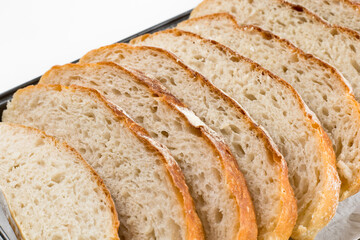 Freshly homemade bread sliced on a baking paper in a baking tray, light and airy inside with a crunchy rustic crust.