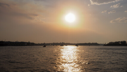 Sydney harbor view with orange sunset and silhouette of the boats and far islands.