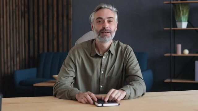 Front View of Confident Mature Vlogger, Blogger, Coach, Mentor, Businessman is talking to the Camera. Handsome Freelancer Businessman is holding Online Conference from Home, wearing Casual Shirts.