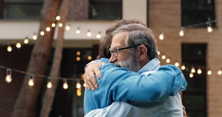 Cheerful happy Caucasian man meeting with old father and hugging at back yard of house. Family dinner outdoors on background. Senior dad with adult son in hugs. Generations. Two men embracing. - Powered by Adobe