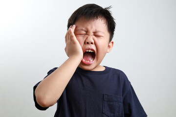 Portrait of a 7-year-old Asian boy suffering from a toothache, dental problem.