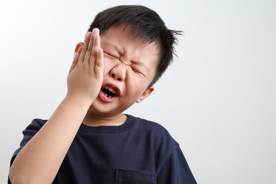 Portrait of a 7-year-old Asian boy suffering from a toothache, dental problem.