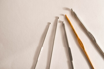 Crochet hooks gray and gold color leat in a row on a light background