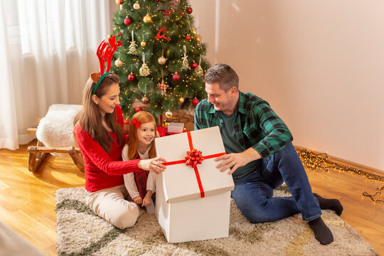 Little girl opening Christmas presents with her parents