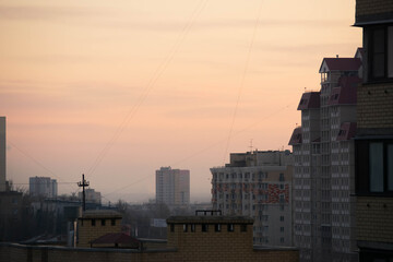 Warm dawn sky against the background of silhouettes of houses.