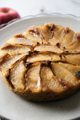 Upside-Down Apple Cake set on white cafe table background.