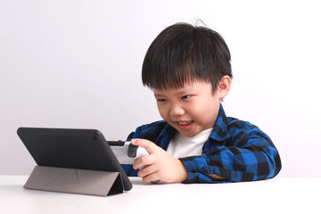 Portrait of a 9-year-old Asian Boy playing video game with a game controller at his desk at home.