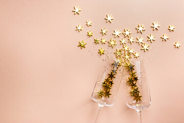 Champagne glasses with golden glittering splashes on pink background. Flat lay, top view, trendy christmas concept.