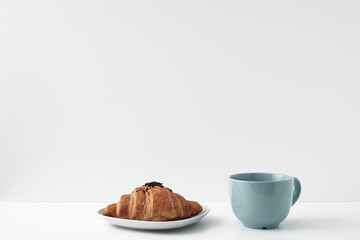 Blue mug and croissants on a white background. Eco-friendly and natural materials in the decor, dessert. Copy space, mock up.