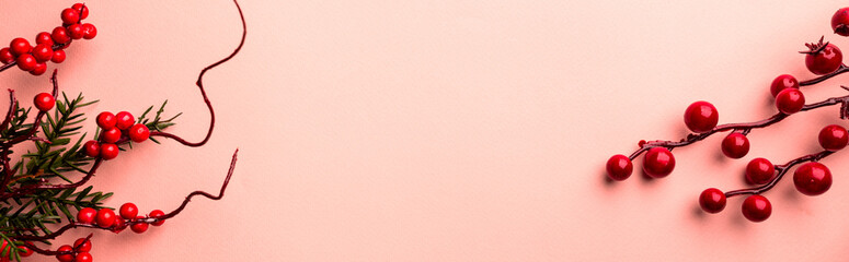Christmas holidays composition with christmas decorations, red berries branches on pink background with copy space, top view