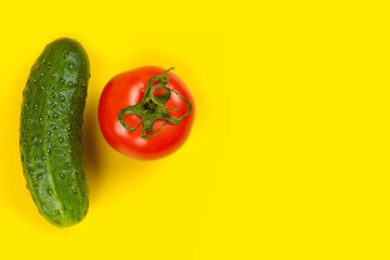 Beautiful fresh cucumber and tomato on yellow background. Ripe vegetables
