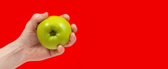 Hand holding tasty organic green delicious apple Isolated on red Background