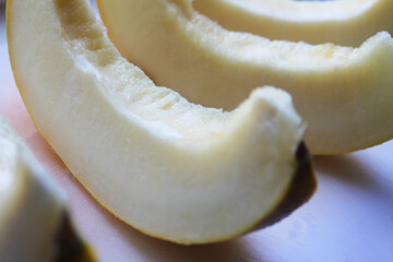 Ripe melon, pitted and cut into slices, close-up, side view. The slices are laid out in a row on a gray surface. Summer season.