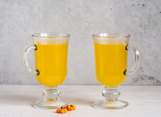 A beautiful healthy drink from sea buckthorn in two glasses on a light background.