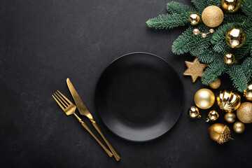 Christmas flat lay background with empty black plate, golden cutlery, christmas tree and toys. Top...
