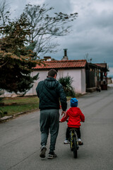 A father teaches his kid child boy how to ride a bike. Bike riding lessons. 