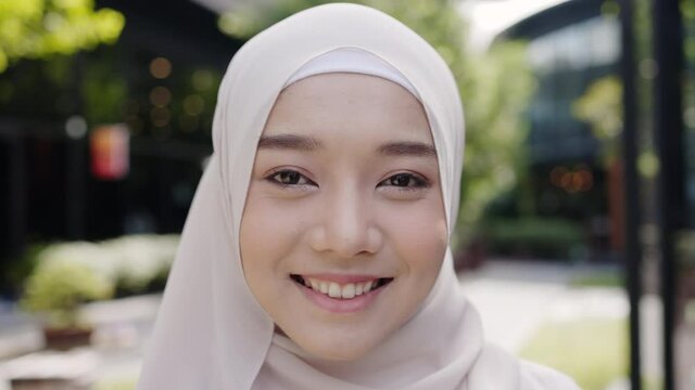 Close up of head of Muslim woman wearing a hijab. Have a beautiful face With a happy smile Standing in the summer garden. Good dental health must be maintained. Concept Health care