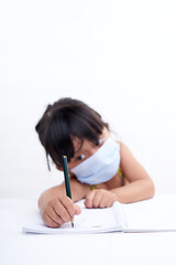 Close-up little girl hand writing in notebook, Wearing a protective face mask