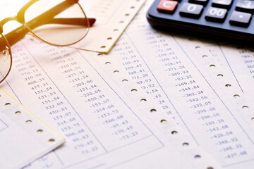 Budget loss figures on a pile of papers with glasses and calculator is background.