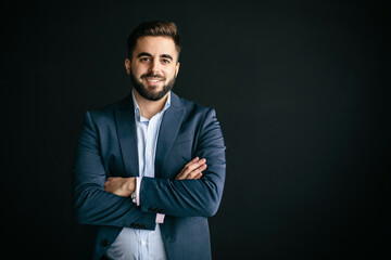 Fototapeta premium Young man, with jacket and shirt, looking like an entrepreneur, smiling, arms crossed. In a wall of the street background. Work and young entrepreneurs concept