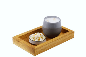 Drewniana taca z glinianym naczyniem z napełnionym żurkiem obok w miseczce kostki sera z warzywami, całośc na białym tle © JDziedzic