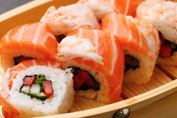 Sushi roll covered with salmon and prawn close up