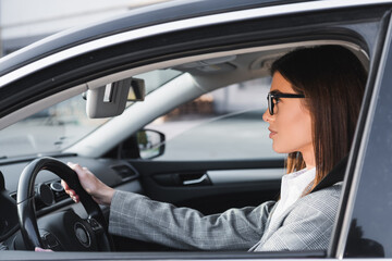 Fototapeta na wymiar side of businesswoman in eyeglasses looking ahead while driving car