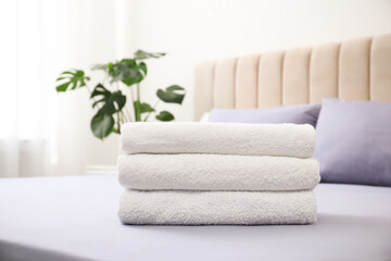 Fototapeta na wymiar Stack of clean towels on bed indoors