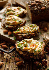 Buckwheat bread sandwiches with hummus and olive oil, sprinkled with chopped parsley and paprika powder on a board close-up.  Healthy vegan and gluten-free  food