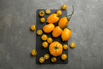 Ripe yellow tomatoes on grey table, flat lay
