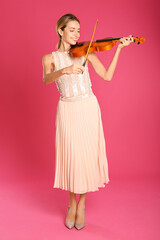 Beautiful woman playing violin on pink background