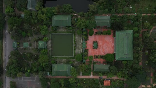 aerial top down tracking shot of ancient Buddhist temple, gardens and street with traffic in south Vietnam
