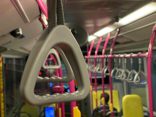 Fototapeta na wymiar Close up of a handrail in a rather empty bus in Singapore at night