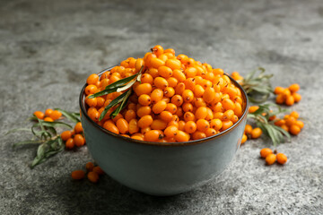 Fresh ripe sea buckthorn in bowl on grey table