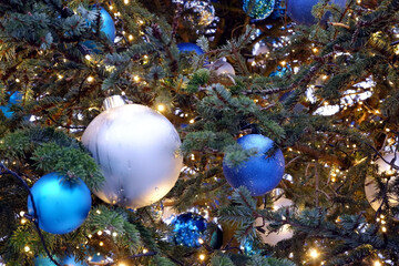 Fototapeta na wymiar Blue and silver christmas balls and lights on a christmas tree close up view