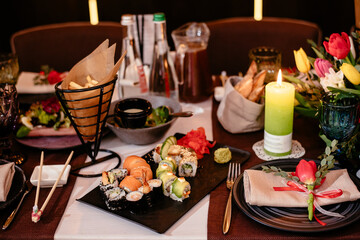 Sushi in a restaurant on a banquet table. Festive table setting with plates, cutlery and snacks. Elegant stylish table setting.