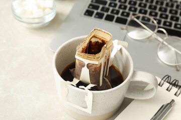 Cup with drip coffee bag on light grey table, closeup