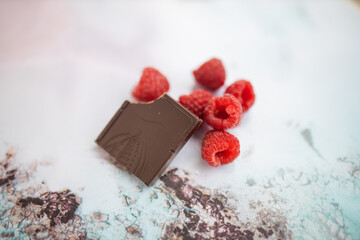 Bitten chocolate bar and raspberries on a colorful placemat