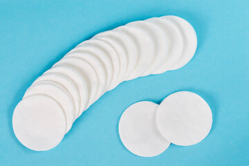 White organic cotton pads on a blue background.
