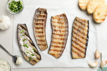 Delicious grilled eggplant slices with sauce on grey table, flat lay
