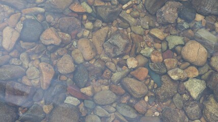 Small and large rocks placed on the ground underwater, close-up view.