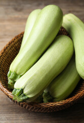 Basket of ripe zucchinis on wooden table, closeup